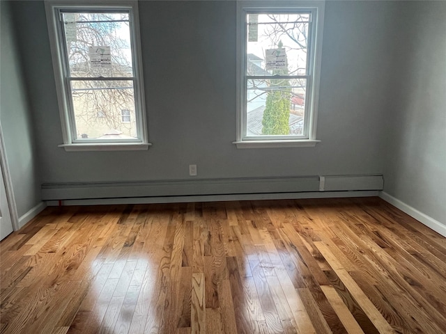 unfurnished room featuring light hardwood / wood-style floors and a baseboard heating unit