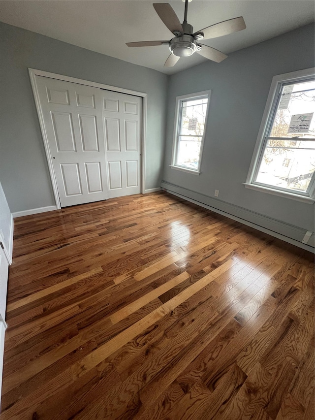 unfurnished bedroom featuring ceiling fan, a closet, and hardwood / wood-style flooring