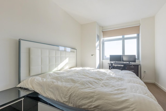 bedroom with vaulted ceiling and hardwood / wood-style flooring