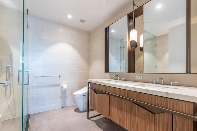 bathroom featuring vanity, tile patterned floors, toilet, tile walls, and a shower with shower door