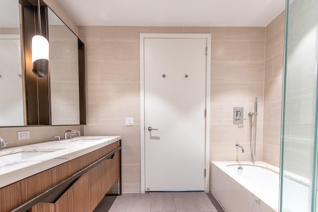 bathroom featuring tile patterned flooring, vanity, tile walls, and tiled shower / bath