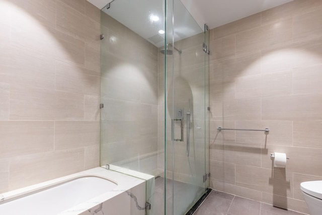 bathroom with tile patterned flooring, toilet, an enclosed shower, and tile walls