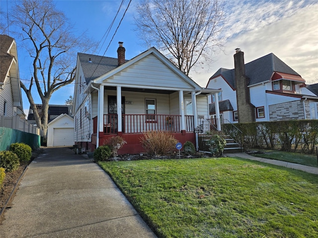 bungalow-style house featuring covered porch, a garage, an outbuilding, and a front yard