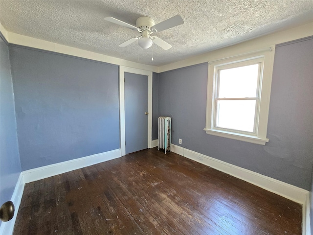 spare room featuring radiator heating unit, a textured ceiling, ceiling fan, and dark wood-type flooring