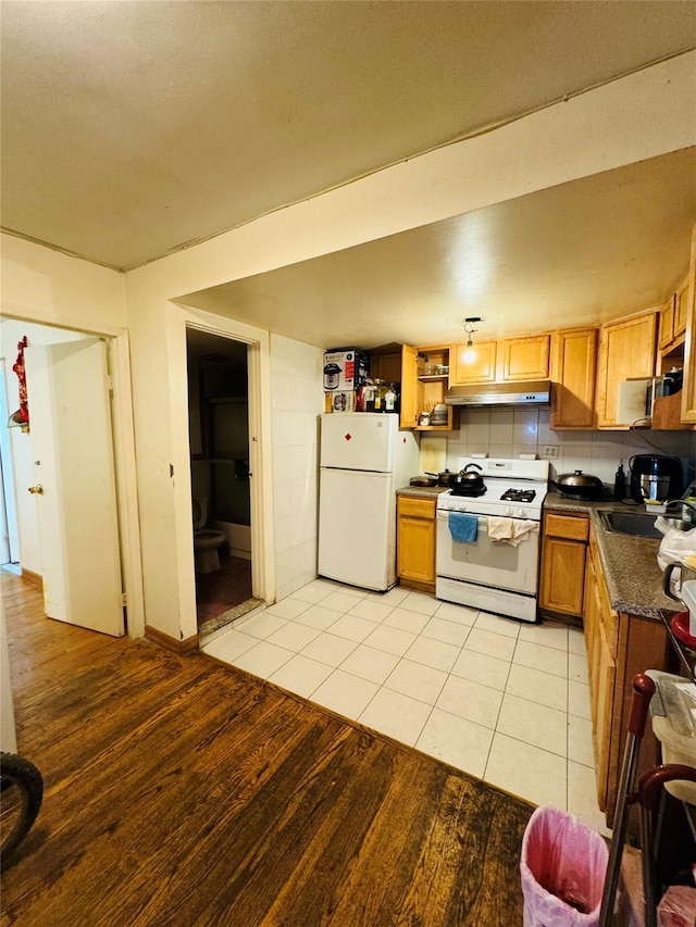 kitchen featuring light tile patterned floors, white appliances, backsplash, and sink