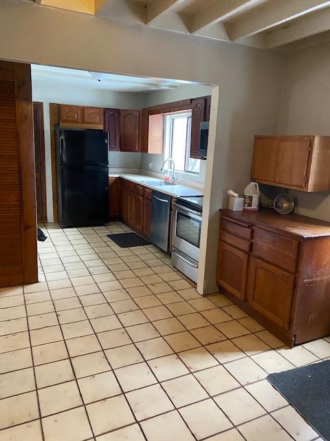 kitchen featuring stove, black fridge, sink, stainless steel dishwasher, and light tile patterned flooring