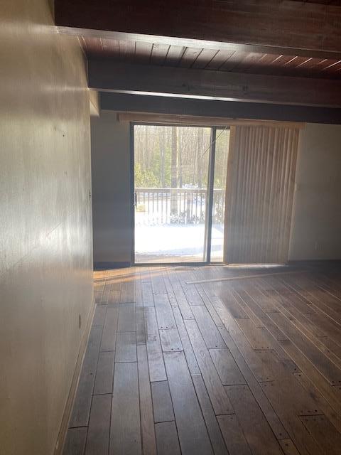 unfurnished room featuring beam ceiling, dark hardwood / wood-style floors, and wood ceiling