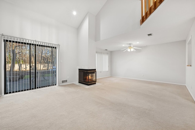 unfurnished living room with a multi sided fireplace, light colored carpet, high vaulted ceiling, and ceiling fan