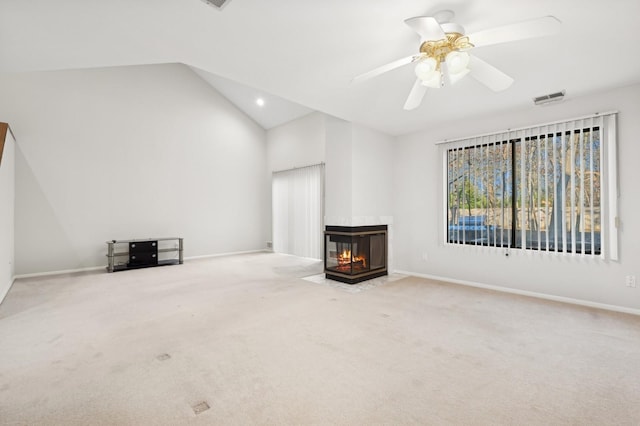 unfurnished living room with ceiling fan, a multi sided fireplace, lofted ceiling, and carpet floors