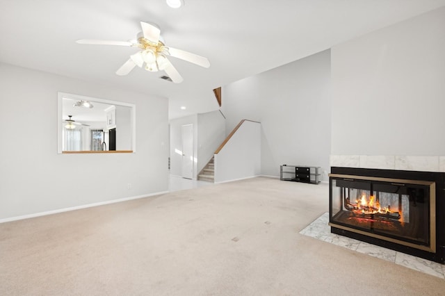 unfurnished living room featuring a tile fireplace, light colored carpet, and ceiling fan