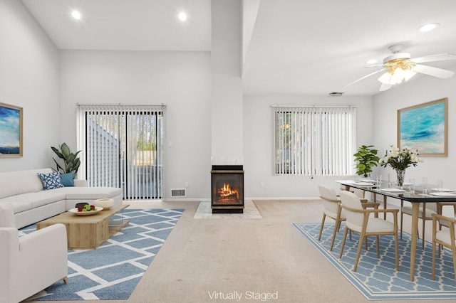 carpeted living room with ceiling fan, a fireplace, and plenty of natural light