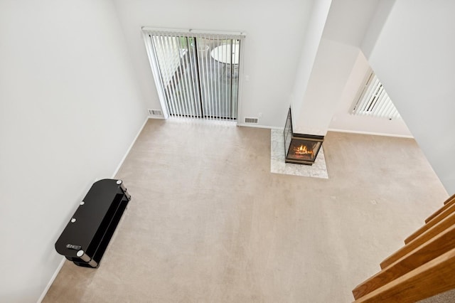 unfurnished living room featuring a multi sided fireplace and light carpet