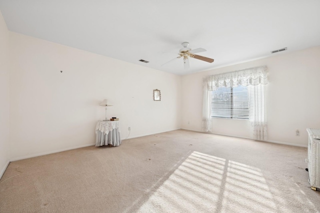 spare room with ceiling fan and light colored carpet