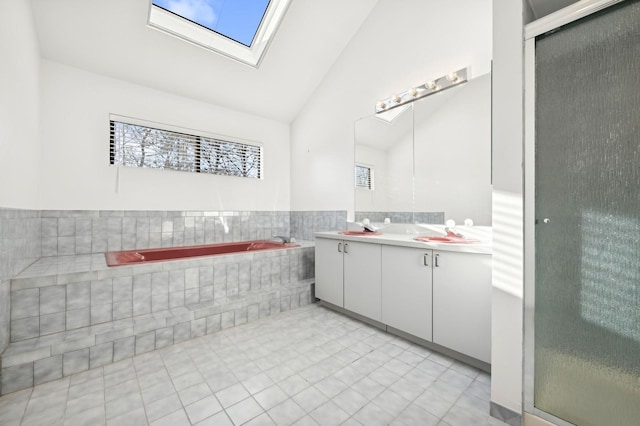 bathroom featuring lofted ceiling with skylight, tile patterned flooring, vanity, and plenty of natural light