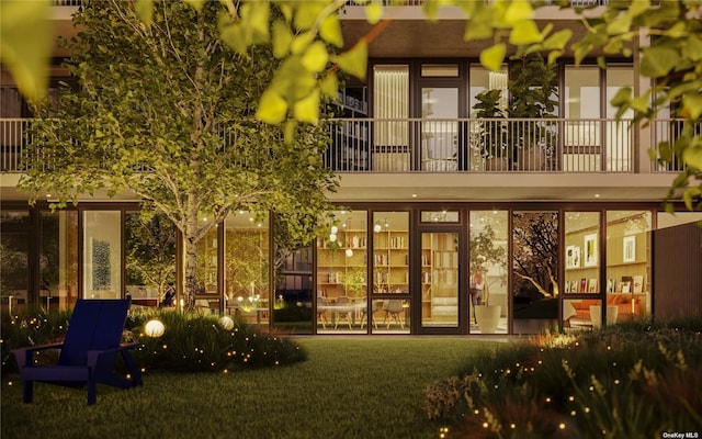 rear view of property with a yard and a balcony