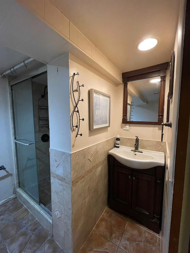 bathroom featuring vanity, a shower with door, and tile walls