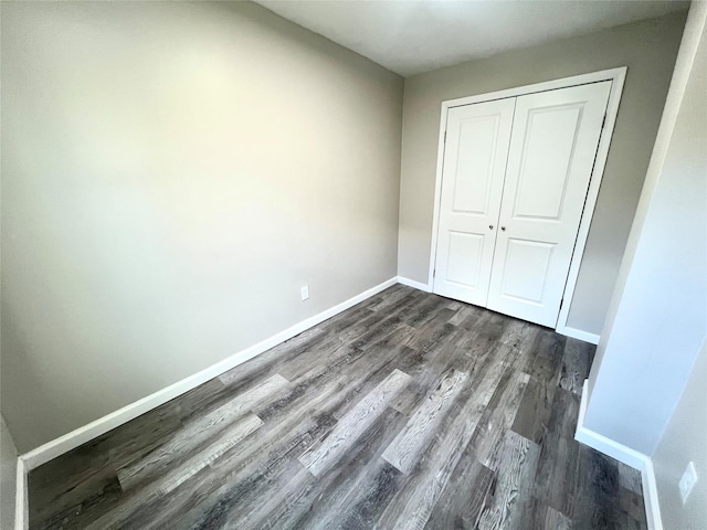 unfurnished bedroom with dark hardwood / wood-style flooring and a closet