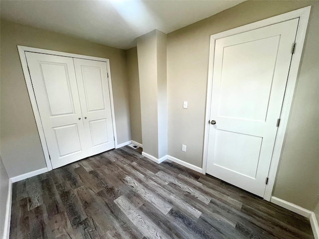 unfurnished bedroom featuring dark hardwood / wood-style flooring and a closet