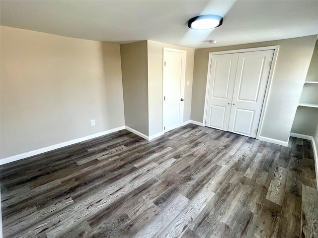 unfurnished bedroom with dark wood-type flooring and a closet