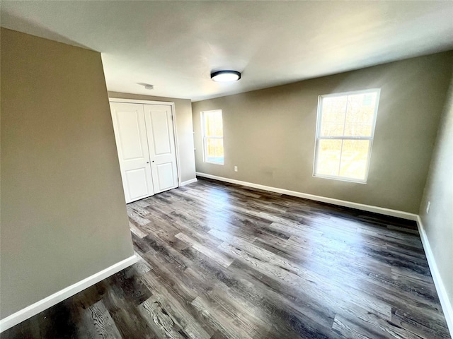 unfurnished bedroom with dark wood-type flooring and a closet