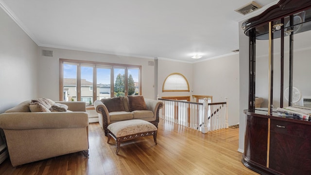 living room with light hardwood / wood-style floors, ornamental molding, and a baseboard heating unit