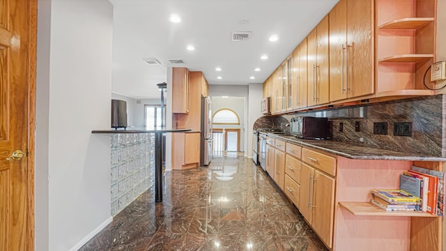 kitchen with kitchen peninsula, backsplash, stainless steel appliances, light brown cabinets, and dark stone countertops