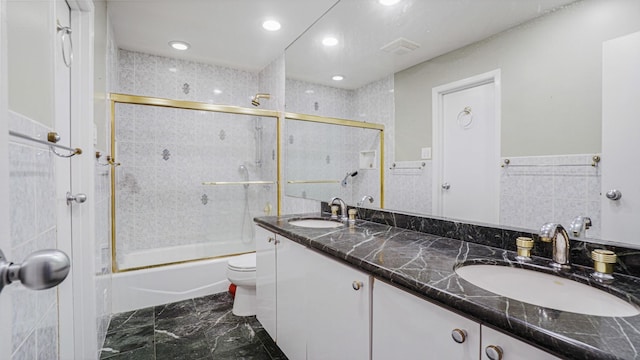 full bathroom with vanity, toilet, tile walls, and enclosed tub / shower combo