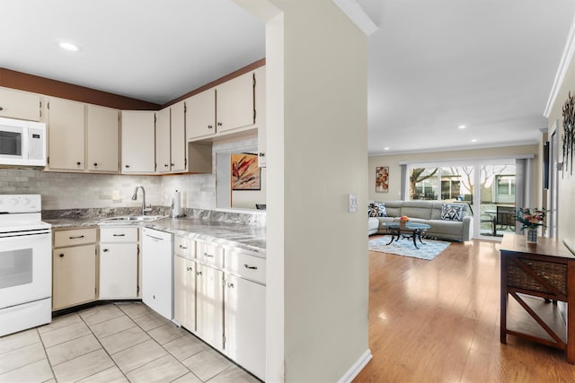 kitchen with white appliances, backsplash, crown molding, sink, and white cabinetry