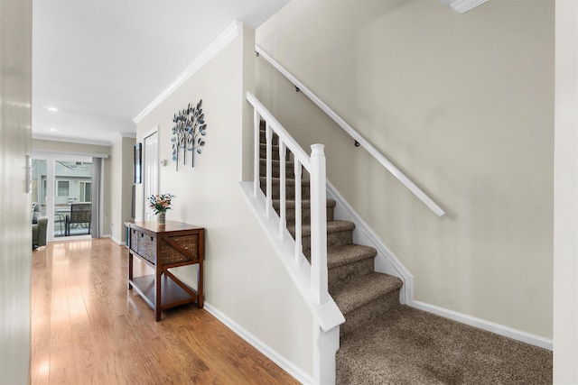 stairs featuring wood-type flooring and ornamental molding