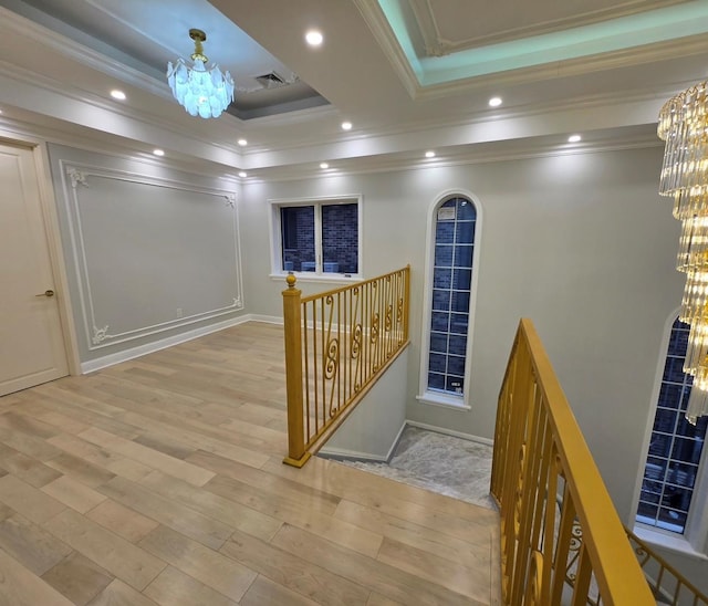 hall featuring crown molding, an inviting chandelier, and light wood-type flooring