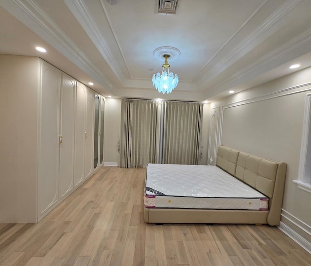 bedroom featuring a raised ceiling, light hardwood / wood-style flooring, crown molding, and a notable chandelier