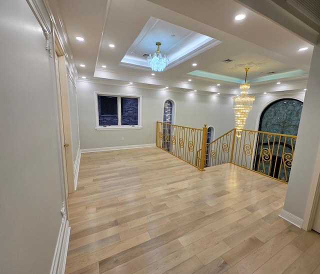 unfurnished room with light hardwood / wood-style floors, a raised ceiling, and a chandelier