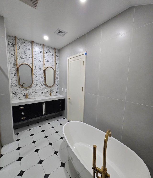 bathroom featuring vanity, a bath, and tile walls