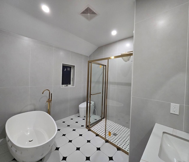 bathroom with vaulted ceiling, a shower with door, tile walls, and toilet