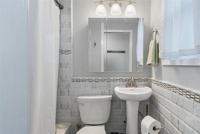 bathroom with curtained shower, tile walls, and toilet