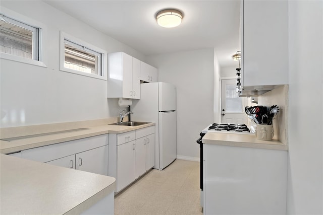 kitchen with white cabinets, cooktop, white refrigerator, and sink