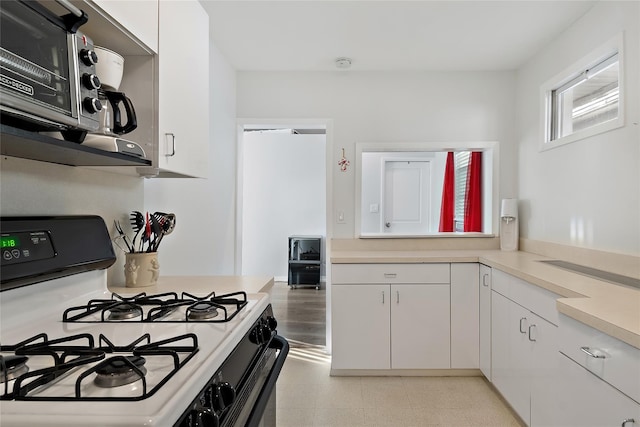 kitchen featuring white cabinets and range with gas cooktop