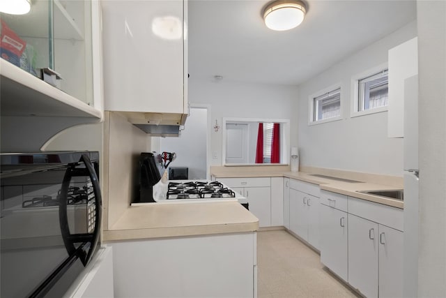 kitchen featuring wall oven, white cabinetry, sink, and range