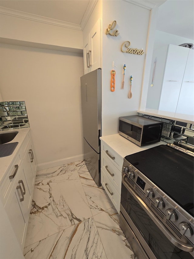 kitchen with white cabinets, crown molding, and stainless steel appliances