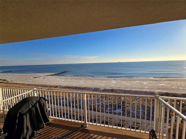 balcony featuring a beach view, a water view, and a grill