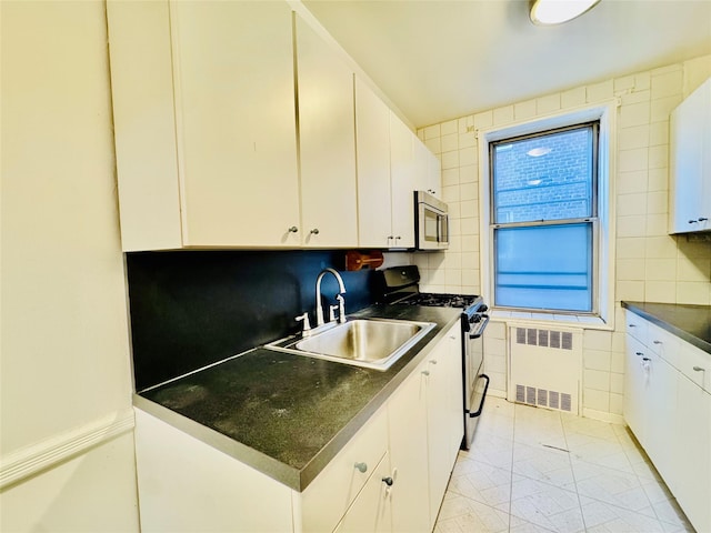 kitchen with radiator, sink, stainless steel appliances, backsplash, and white cabinets