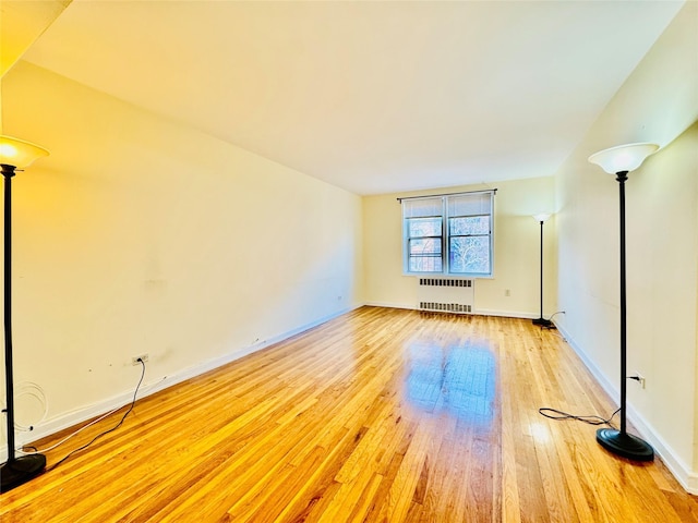 empty room featuring light wood-type flooring and radiator