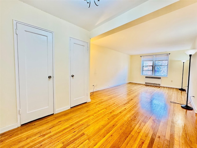 additional living space with radiator and light hardwood / wood-style flooring