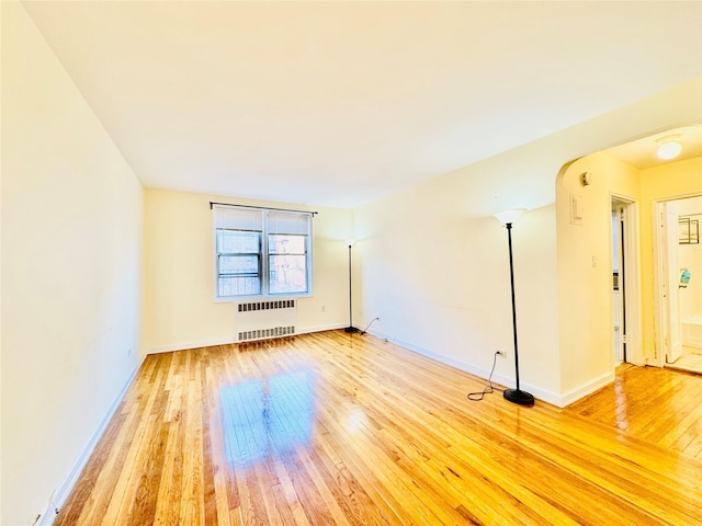 empty room with radiator heating unit and hardwood / wood-style flooring