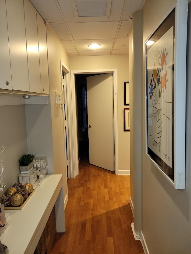 hallway with a paneled ceiling and light wood-type flooring