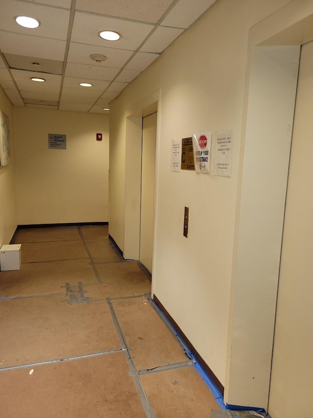 hall featuring a paneled ceiling and tile patterned flooring