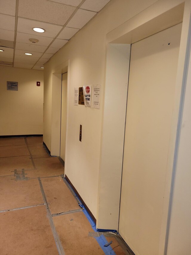 hall featuring elevator, a drop ceiling, and tile patterned flooring