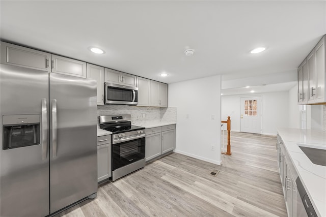 kitchen featuring gray cabinetry, appliances with stainless steel finishes, and light hardwood / wood-style flooring