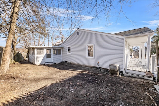 rear view of house with central AC unit, a wooden deck, and a sunroom