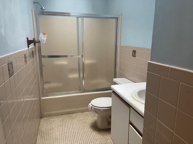 full bathroom featuring shower / bath combination with glass door, vanity, tile patterned floors, and tile walls